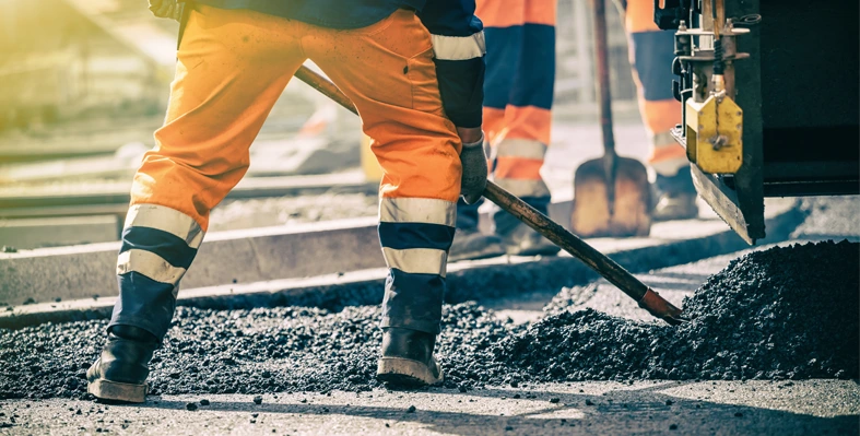 Road construction in action with a worker laying tarmac.