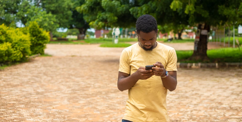 A man using his mobile phone in a park. 