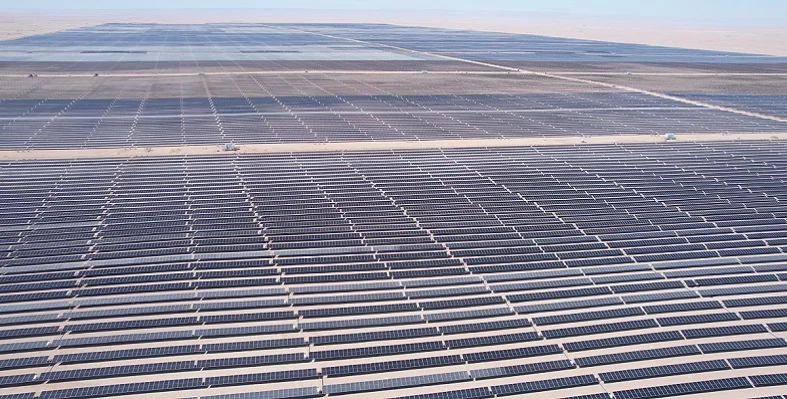 A wide shot of a large solar plant with thousands of panels in the desert.