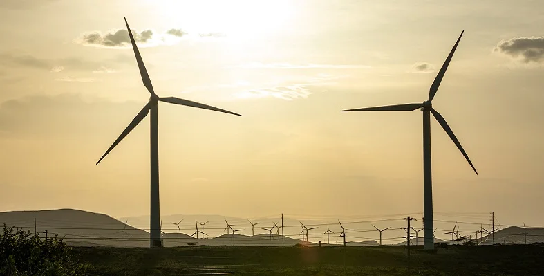 Wind turbines against a sunsent.