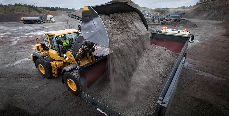 A Volvo CE wheel loader putting gravel into a truck.