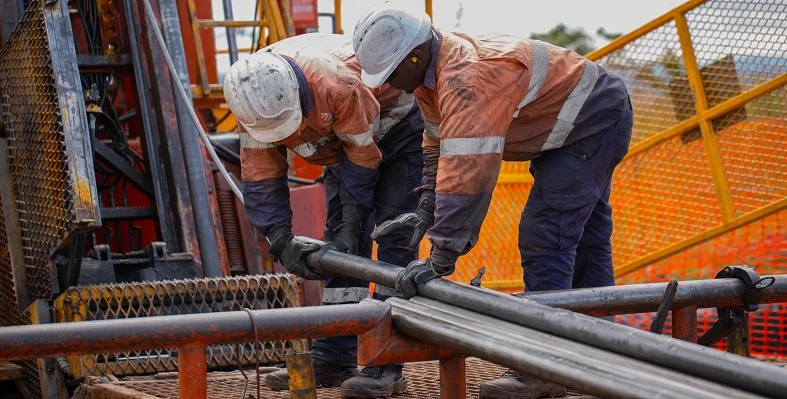 Two African miners working on drilling operations.