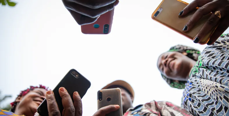 People stood in a circle looking at their phones.