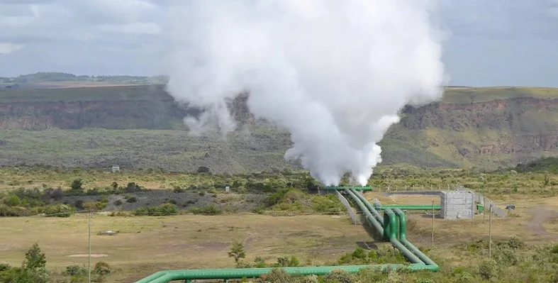 Steam rising from a geothermal well with pipes leading from it.