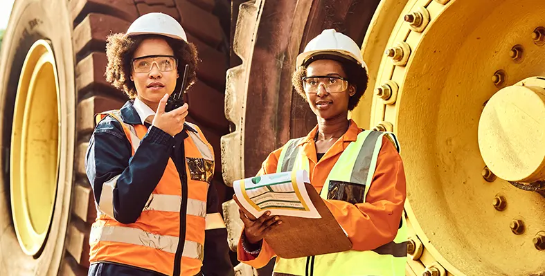 Two_female_workers_next_to_ large_mining_truck