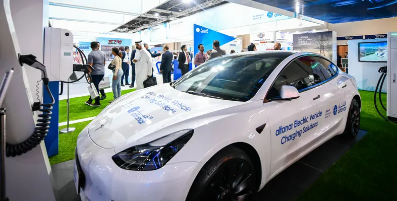 Electric_vehicle_and_charging_point_on_trade_show_floor_with_people_in_the_background