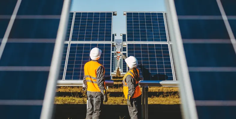 Two men standing infront of solar power station 