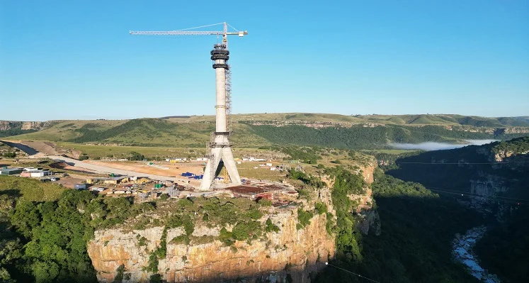 A wide shot of one of the large pylons of the Msikaba bridge in South Africa standing high above the river gorge.