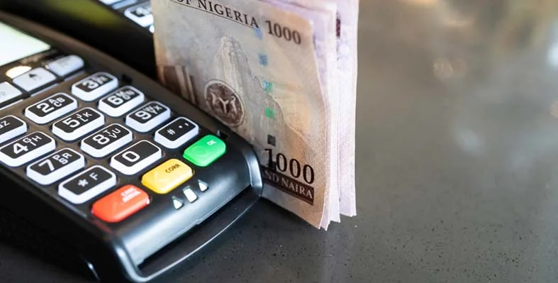 Nigerian_naira_stacked_up_next_to_a_card_reader.