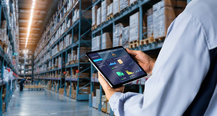 A worker assessing a tablet with warehouse management software. 