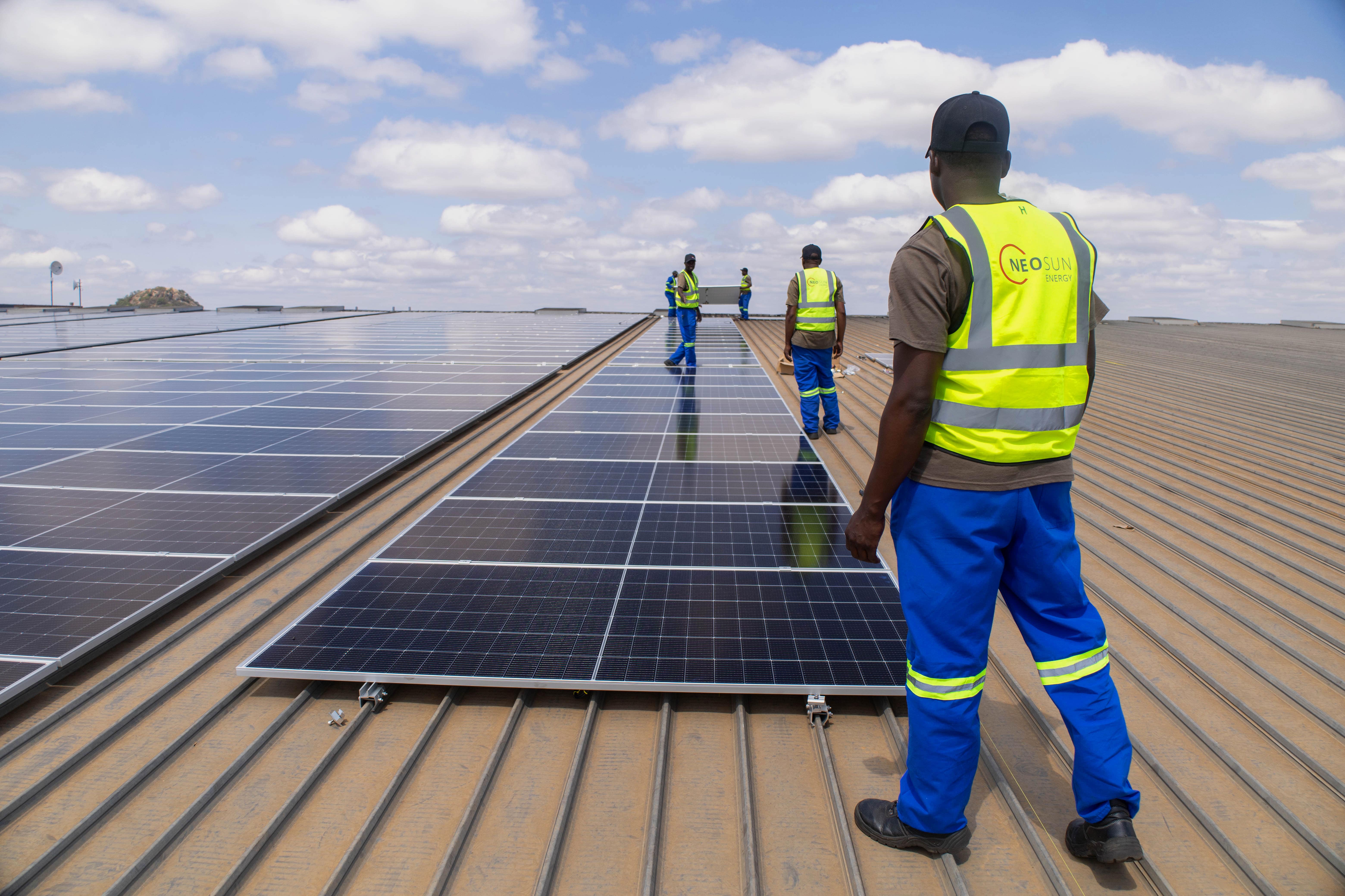 Workers surrounded by solar panels.