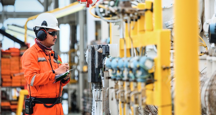 A worker inspecting oil and gas equipment for certification.