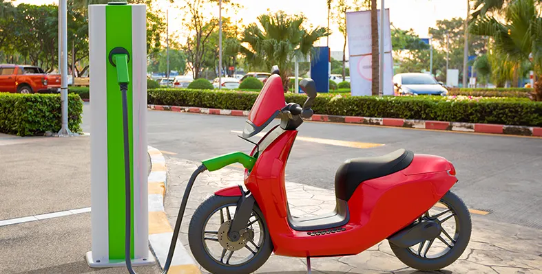 A Cambridge University report highlights how electric motorcycles can reduce air pollution, improve health, and transform urban mobility in Uganda. (Image source: Adobe Stock) E-Mototcyle_at_the_charging_booth_on_the_road