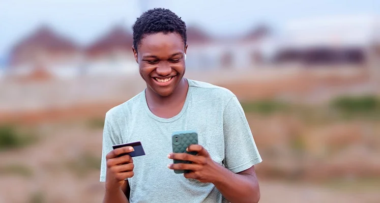 Young_man_shopping_smiling_at_phone_with_credit_card