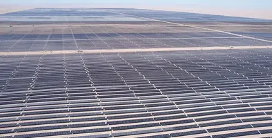 A wide shot of a large solar plant with thousands of panels in the desert.