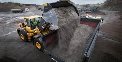 A Volvo CE wheel loader putting gravel into a truck.