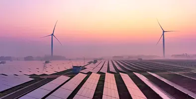 Wind turbines in the background with solar panels in the foreground. 