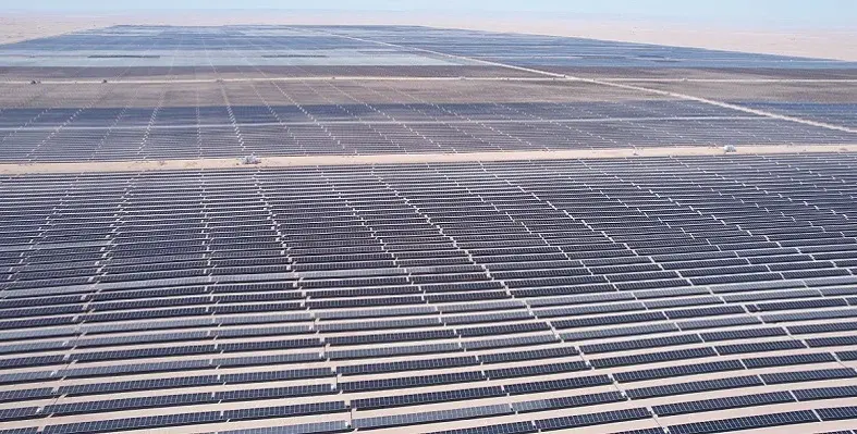 A wide shot of a large solar plant with thousands of panels in the desert.