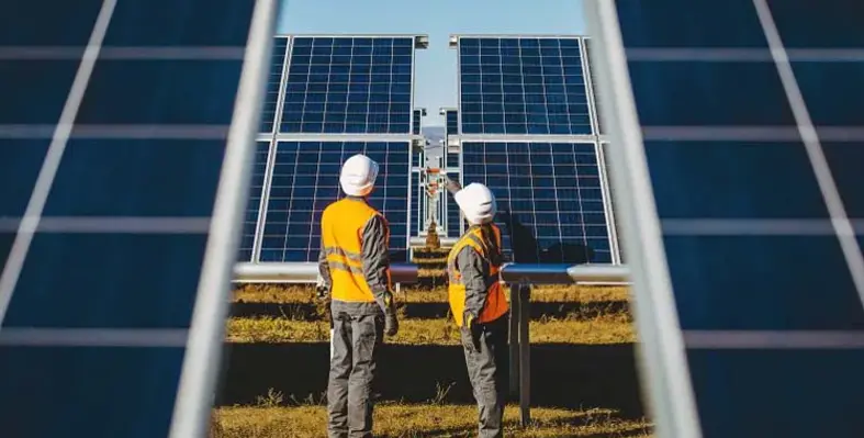 Two workers inspecting large solar panels. 