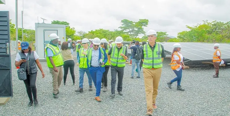 Leaders of the involved organisations walking through a concrete area with solar panels in the background.