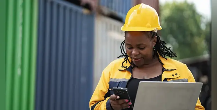 African-woman-logistics-worker-notebook-computer-checking-container