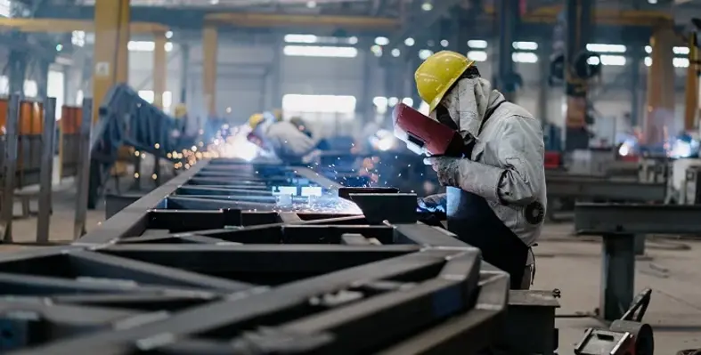 A worker welding iron on a manufacturing facility floor. 