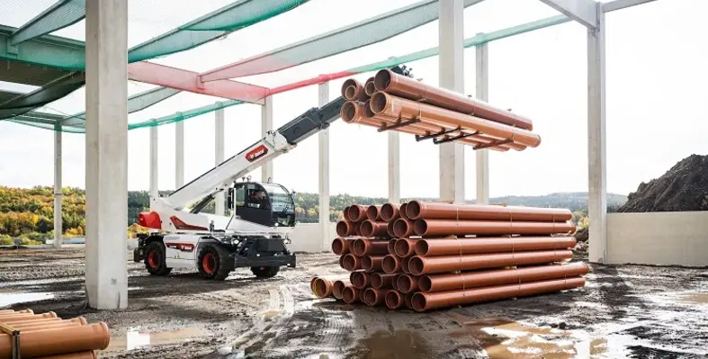 A new rotary telehandler from Bobcat lifting pipes on a construction site.