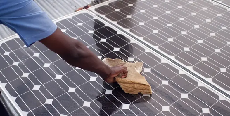 A man wiping down a solar panel with a cloth. 