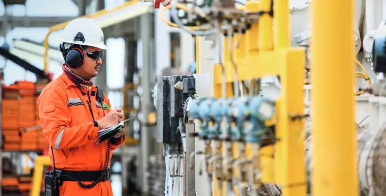 A worker inspecting oil and gas equipment for certification.