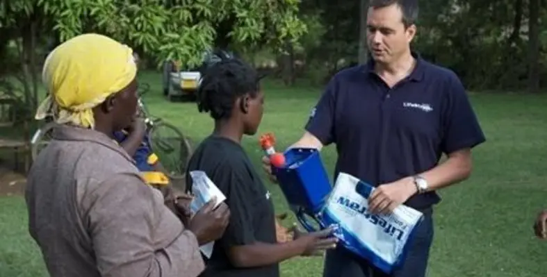 Mikkel Vestergard Frandsen shows a Family LifeStraw water filter to a recipient family. (Image source: Stephen Williams)
